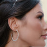 Side view of model wearing the Lila Silver Bead Hoop Earrings that feature open medium hoop with silver beads.