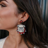 Side view of model wearing the Bulldog Game Day Earrings that feature bulldog face shaped dangle earrings with red and white glitter details.