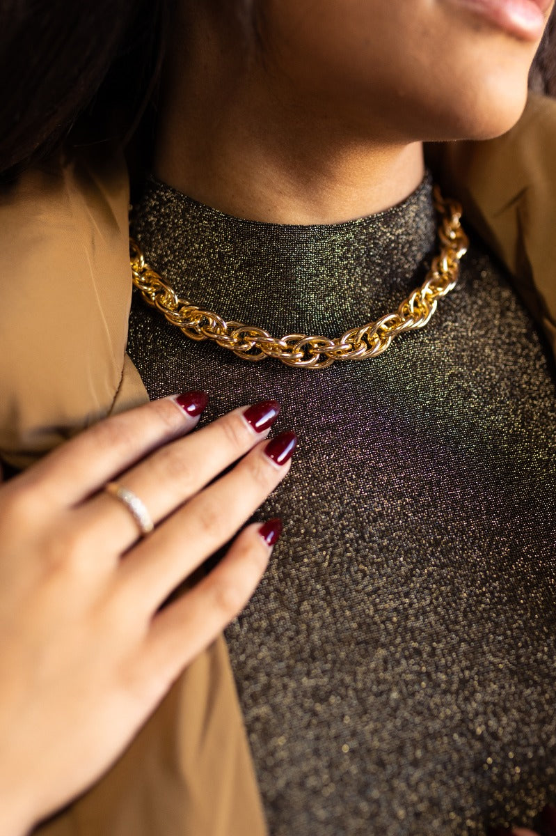 Close up view of model wearing the Everly Gold Chain Link Necklace which features shiny gold chain links with an adjustable clasp closure.