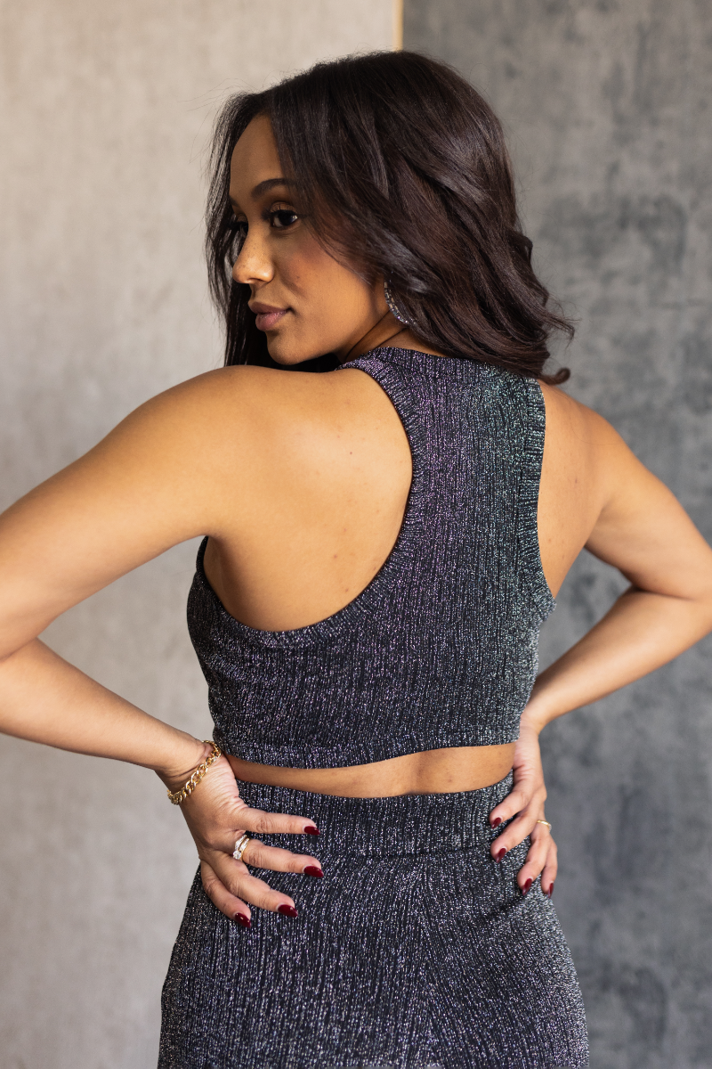 Back view of model wearing the Monroe Black & Silver Tank Top that has black and silver mesh fabric, a cropped waist, a high neckline and a sleeveless body.