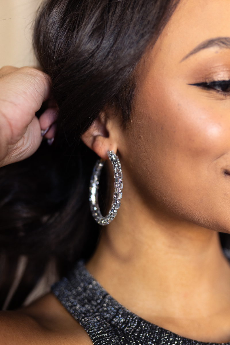 Close up view of model wearing the Stella Rhinestone Closed Large Hoop which features large closed hoops with clear rectangle and circle stones.