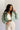 front view of model wearing the Mckinley Mint Cropped Puffer Jacket that has mint green puffer fabric, a cropped waist, a front zipper with snaps, a hood, and long sleeves.