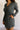 Close front view of model wearing the Ezra Grey Green Long Sleeve Romper that has grey green knit fabric, pockets, an elastic waist, a front zipper, a hood, a skirt with fitted shorts , and long sleeves.