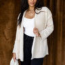 front view of model wearing the Elena Beige Open Front Cardigan that has beige knit fabric, two front pockets, ribbed trim , an open front, and long sleeves.