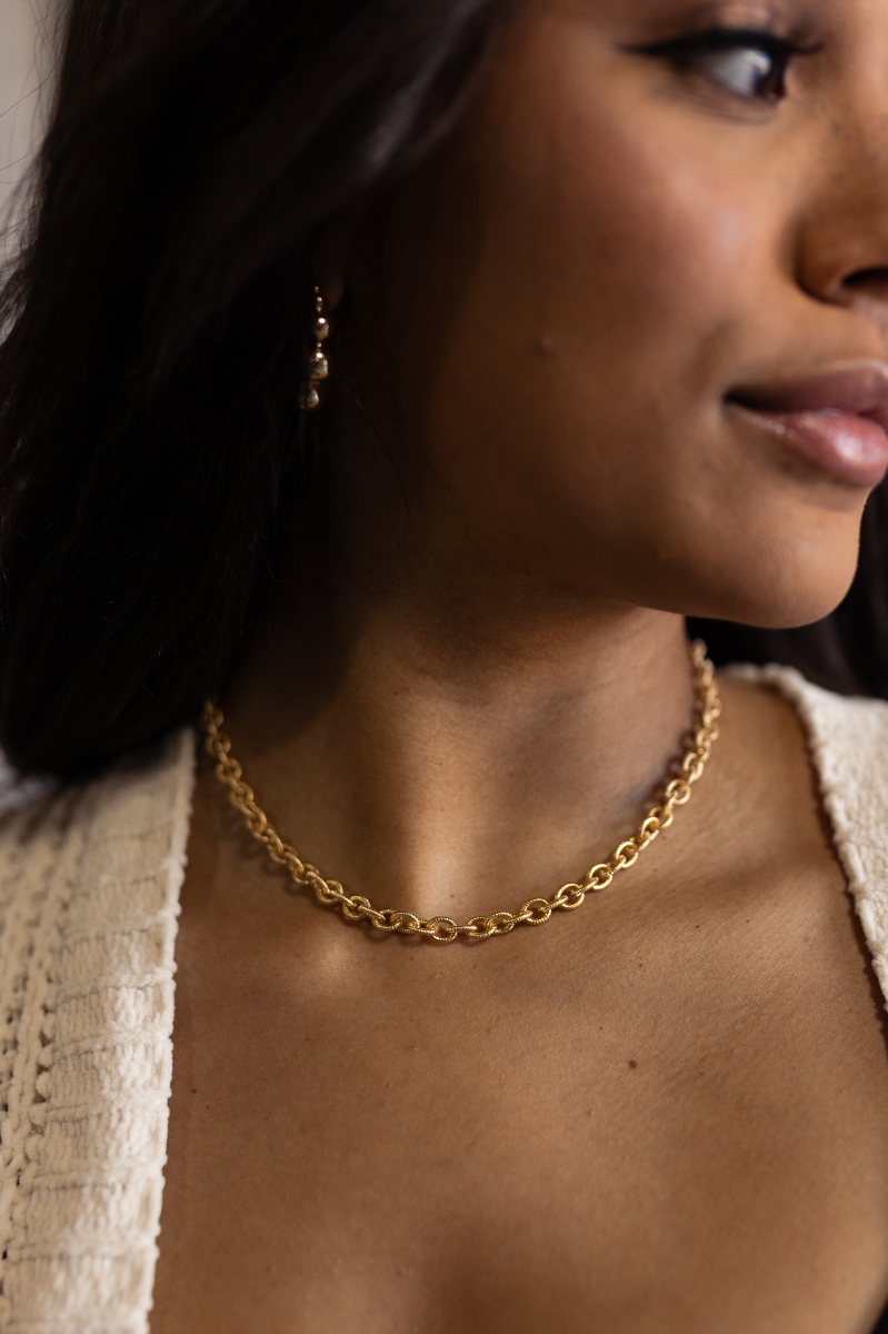 Close up view model wewaring the Skylar Gold Textured Chain Link Necklace which features one layer of gold circle chains linked together.