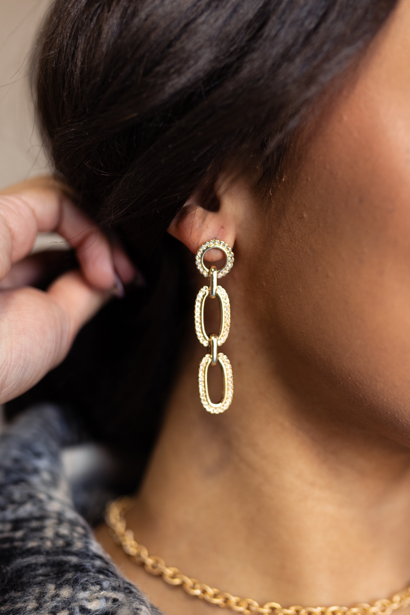 Side view of model wearing the Grace Gold and Rhinestone Chain Link Dangle Earring which features gold dangle chain links liked together with clear stone details.