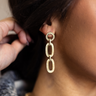 Side view of model wearing the Grace Gold and Rhinestone Chain Link Dangle Earring which features gold dangle chain links liked together with clear stone details.