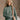 Front view of model wearing The Jennifer Sage Mock Neck Sweatshirt features sage green knit fabric, two front slit pockets, ribbed hem, high neckline and long sleeves with cuffs.
