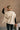 Back view of The Courtney Cream Sherpa Vest features beige textured fabric, two front slit pockets, side ties, monochrome button up closure, high neckline and sleeveless.