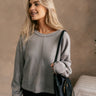 Front view of model wearing The Heather Ribbed Long Sleeve Top in Grey features grey knit fabric, textured details, thick hem, round neckline, dropped shoulders and long balloon sleeves with cuffs.