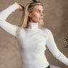 Front view of model wearing The Elora Off White Long Sleeve Ribbed Turtleneck features off white ribbed fabric, turtleneck neckline and long sleeves.