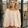 Front view of model wearing The Bella Cream Long Sleeve Top features cream gauze fabric, peplum body, round neckline, long puff sleeves with elastic cuffs and open back with tie closure.