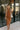 Front view of model wearing The Maria A-Symmetrical Cognac Party Dress features pale brown with a gold shimmer fabric, asymmetrical hem, pale brown lining, side cut out design with ruched design, one -shoulder strap, monochrome side zipper with hook closu