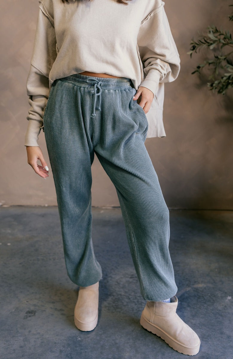 Front view of model wearing the Myla Grey Green Drawstring Jogger Pants which features grey green waffle knit fabric, two front pockets, an elastic waistband with drawstring ties, and jogger pant legs with thick hem.