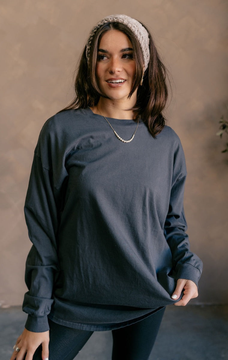 Front view of model wearing the Vira Black Long Sleeve Sweatshirt which features washed black knit fabric, a round neckline, dropped shoulders, and long sleeves with cuffs.