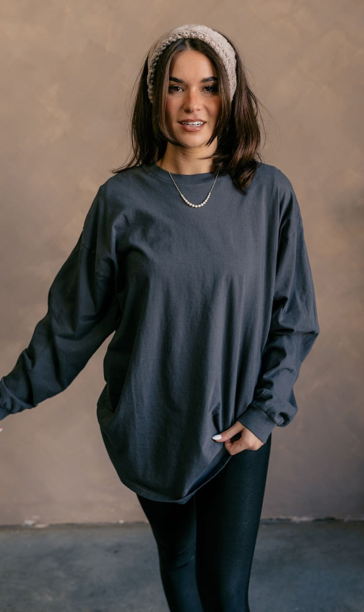 Front view of model wearing the Vira Black Long Sleeve Sweatshirt which features washed black knit fabric, a round neckline, dropped shoulders, and long sleeves with cuffs.