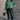 Full body view of model wearing the Merry Green Ribbed Long Sleeve Sweater which features green and light green ribbed fabric, thick hem, a round neckline, a graphic that says "MERRY" in white outline, dropped shoulders, and long sleeves with ribbed cuffs