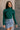 Front view of model wearing the Elora Green Long Sleeve Ribbed Turtleneck that has pine green ribbed fabric, a turtleneck neckline, and long sleeves.
