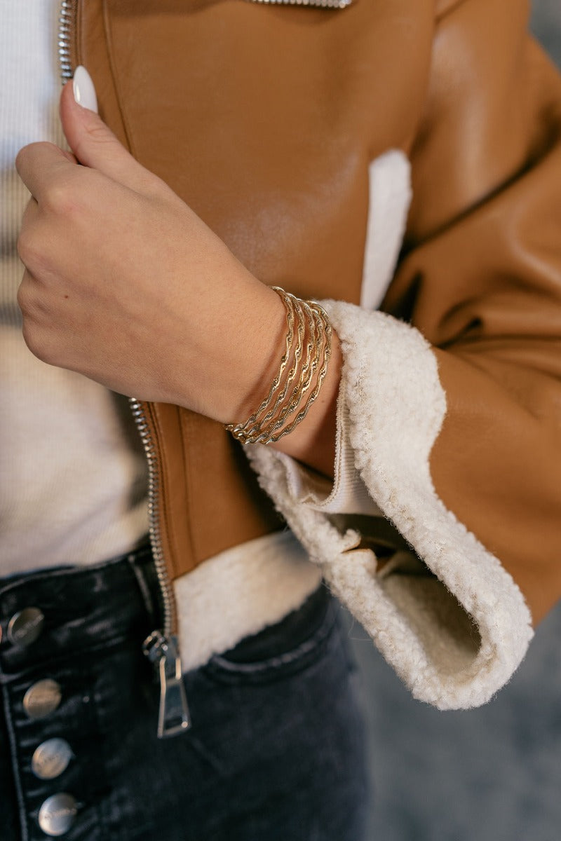 Close up view of model wearing the Ciara Twisted Gold Layered Bracelet which features gold bangle with twisted details.