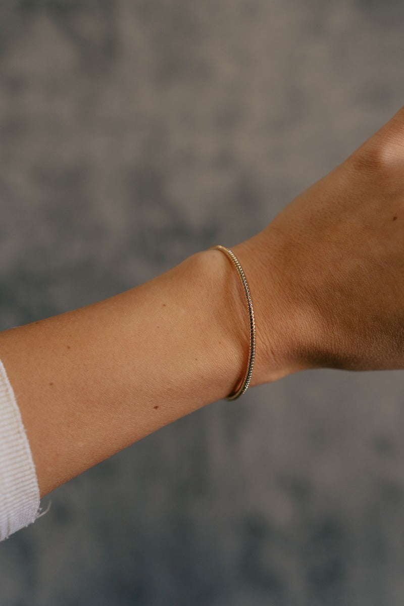 Front view of model wearing the Harper Gold Textured Bangle Bracelet which features gold bangle with cobra design.