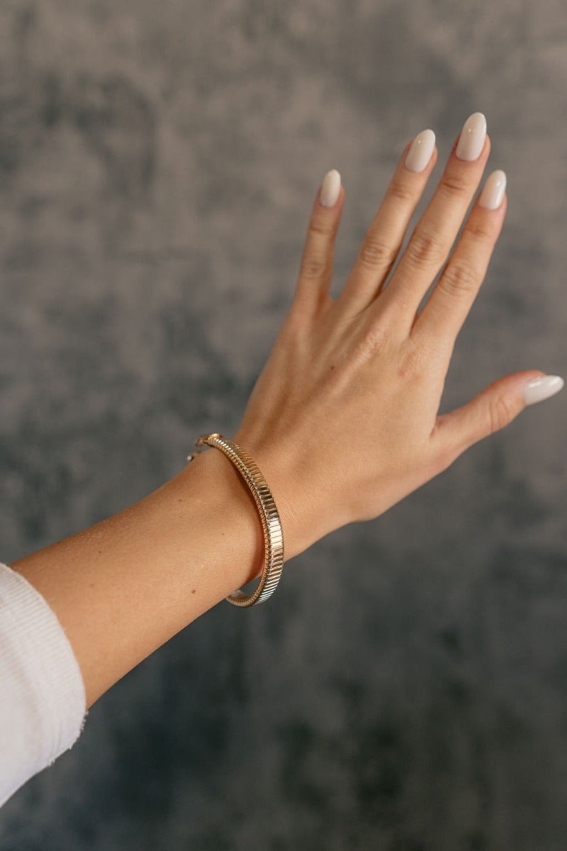 Front view of model wearing the Nessa Gold Textured Adjustable Bracelet which features gold cobra stretch design with adjustable clasp closure.