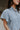 Upper front view of model wearing the Cynthia Blue Short Sleeve Button Up Top that has light blue tencel fabric, light brown stitching , grey tortoise buttons, a collared neckline, and short flare sleeves.