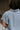 Upper back view of model wearing the Cynthia Blue Short Sleeve Button Up Top that has light blue tencel fabric, light brown stitching , grey tortoise buttons, a collared neckline, and short flare sleeves.