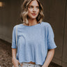 Front view of model wearing the Kassidy Blue Cropped Short Sleeve Top that has blue knit fabric, ribbed hem, a wide cropped fit, a round neckline, dropped shoulders, and short sleeves.