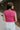 Back view of model wearing the Veronica Hot Pink Sleeveless Sweater that has hot pink knit fabric, a ribbed hem, a round neckline and a sleeveless design.