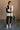 Full body front view of model wearing the Reagan White Oversized Puffer Vest that has white lightweight puffer fabric, a 3 tiered design, white lining, two pockets, a hidden zipper, snaps, a high neck and a sleeveless design.