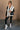 Full body front view of model wearing the Reagan White Oversized Puffer Vest that has white lightweight puffer fabric, a 3 tiered design, white lining, two pockets, a hidden zipper, snaps, a high neck and a sleeveless design.