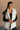 front view of model wearing the Reagan White Oversized Puffer Vest that has white lightweight puffer fabric, a 3 tiered design, white lining, two pockets, a hidden zipper, snaps, a high neck and a sleeveless design.
