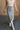 front view of model wearing the Liana Denim Front Slit Midi Skirt that has light wash denim fabric, brown stitching, midi length, a raw hem, and a front slit.