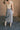 Back view of model wearing the Liana Denim Front Slit Midi Skirt that has light wash denim fabric, brown stitching, midi length, a raw hem, and a front slit.