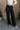 front view of model wearing the Margo Black Denim Cargo Pants that have black cotton fabric, pockets, a front zipper with a button closure, belt loops, and wide legs. 