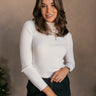 Front view of model wearing the Mila Ivory Ribbed Long Sleeve Top which features ivory ribbed knit fabric, a high neckline, and long sleeves.