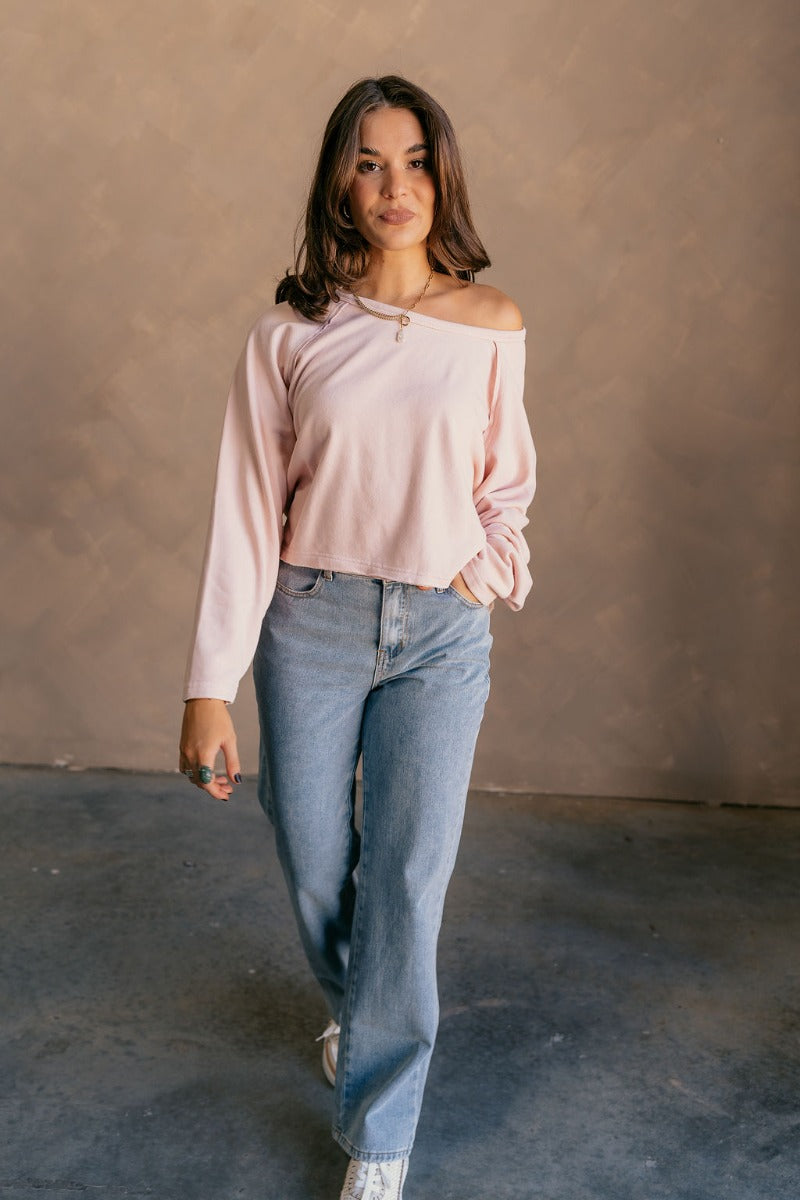 Full body front view of model wearing the Charlotte Light Pink Raglan Sweatshirt that has light dusty pink knit fabric, raw hem details, a round neckline, and long wide sleeves.
