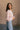 Side view of model wearing the Charlotte Light Pink Raglan Sweatshirt that has light dusty pink knit fabric, raw hem details, a round neckline, and long wide sleeves.