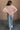 Full body back  view of model wearing the Charlotte Light Pink Raglan Sweatshirt that has light dusty pink knit fabric, raw hem details, a round neckline, and long wide sleeves.
