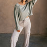 Full body front view of model wearing the Charlotte Sage Green Raglan Sweatshirt that has dusty light sage knit fabric, raw hem details, a round neckline, and long wide sleeves.