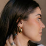 Side view of model wearing the Elodie Gold Scoop Hoop which features small gold scooped, open hoops.