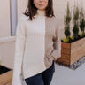 Front view of model wearing the Lillian Taupe & Cream Long Sleeve Sweater which features cream cable knit fabric, taupe ribbed knit fabric, a color block pattern, a ribbed hem, slight slits on each side, a high neckline, and long sleeves with cuffs.