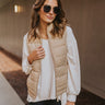 Front view of model wearing the Westward Packable Puffer Vest in Khaki that has khaki puffer fabric, front pockets, a front zipper with a collar, and a sleeveless body. 