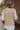 Back view of model wearing the Westward Packable Puffer Vest in Khaki that has khaki puffer fabric, front pockets, a front zipper with a collar, and a sleeveless body. 