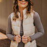 Front view of model wearing the Westward Packable Puffer Vest in Cream that has cream puffer fabric, two front pockets, a front zipper with a collar, and a sleeveless body.