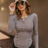 Front view of model wearing the Remember Me Henley Top that has dark grey waffle knit fabric, a lettuce trim hem, a rose gold button up neckline, and long sleeves with lettuce trim