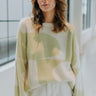 Front view of model wearing the All About It Sweater that has cream and light green knit fabric with a geometric pattern, cream ribbed trim, a round neckline, and long sleeves.