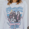 Front view of model wearing the Aerosmith Graphic Tee that has  white knit fabric with a fleece interior, a raw hem, a round neckline and long flare sleeves. Tee features an Aerosmith graphic.