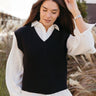 Front view of model wearing the Impress Me Sweater Vest in Black that has black knit fabric, a v-neckline, and ribbed trim.