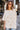 Front view of model wearing the You're A Star Top that has cream cotton fabric with silver sequin stars, an oversized fit, a round neckline, and short sleeves.